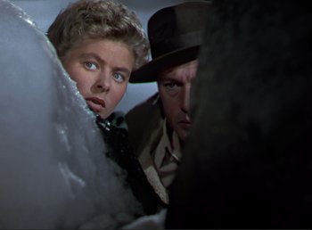 Movie still from “For Whom the Bell Tolls” (1943), directed by Sam Wood – A man and a woman looking out from behind a wall; Close Up shot, Low angle