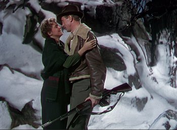 Movie still from “For Whom the Bell Tolls” (1943), directed by Sam Wood – A man and a woman are hugging in the snow; Medium shot, Low angle
