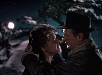 Movie still from “For Whom the Bell Tolls” (1943), directed by Sam Wood – A man and a woman embracing in front of the moon; Medium shot, Low angle
