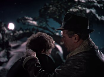 Movie still from “For Whom the Bell Tolls” (1943), directed by Sam Wood – A man and a boy in the dark with a full moon in the background; Medium shot, Over the shoulder angle