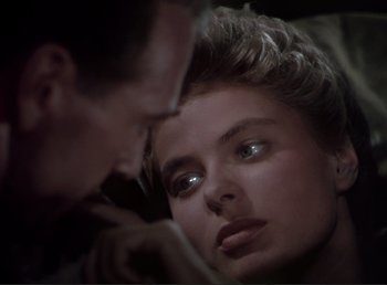 Movie still from “For Whom the Bell Tolls” (1943), directed by Sam Wood – A man and a woman face to face in a dark room; Close Up shot, Over the shoulder angle