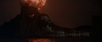 Movie still from “Force 10 from Navarone” (1978), directed by Guy Hamilton – A fire is burning in the night sky over a castle; Extreme Wide shot, Low angle