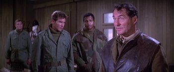 Movie still from “Force 10 from Navarone” (1978), directed by Guy Hamilton – A group of men standing next to each other in a room; Medium shot, Over the shoulder angle