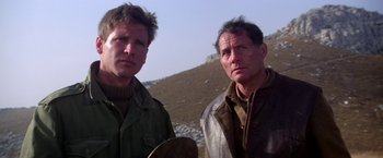 Movie still from “Force 10 from Navarone” (1978), directed by Guy Hamilton – A couple of men standing next to each other on top of a hill; Close Up shot, Low angle