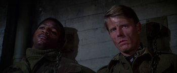 Movie still from “Force 10 from Navarone” (1978), directed by Guy Hamilton – A man and a woman standing next to each other in front of a brick wall; Close Up shot, Over the shoulder angle