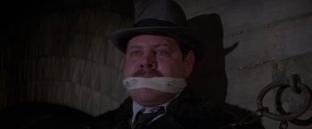 Movie still from “Force 10 from Navarone” (1978), directed by Guy Hamilton – A man in a hat and a tie with his mouth taped shut; Close Up shot, Low angle