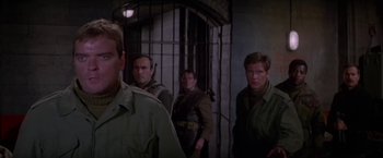 Movie still from “Force 10 from Navarone” (1978), directed by Guy Hamilton – A group of men standing next to each other in a room; Medium shot, Over the shoulder angle