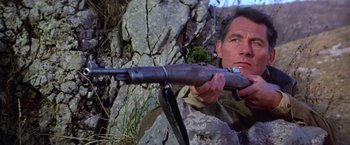 Movie still from “Force 10 from Navarone” (1978), directed by Guy Hamilton – A man is holding a rifle in his hand; Close Up shot, Low angle