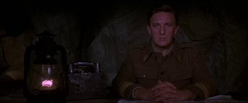 Movie still from “Force 10 from Navarone” (1978), directed by Guy Hamilton – A man sitting at a table in a dark room; Close Up shot, Low angle