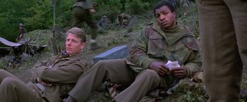Movie still from “Force 10 from Navarone” (1978), directed by Guy Hamilton – Two men sitting on the ground in the grass; Medium shot, Low angle