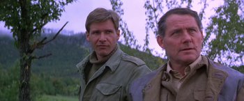 Movie still from “Force 10 from Navarone” (1978), directed by Guy Hamilton – A man standing next to another man in a field; Close Up shot, Low angle