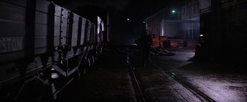 Movie still from “Force 10 from Navarone” (1978), directed by Guy Hamilton – A man standing next to a train on a train track at night; Wide shot, High angle