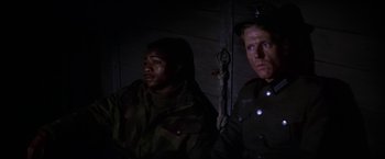 Movie still from “Force 10 from Navarone” (1978), directed by Guy Hamilton – Two men in uniforms are standing in a dark room; Medium shot, High angle
