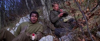 Movie still from “Force 10 from Navarone” (1978), directed by Guy Hamilton – Two men sitting on the ground in the woods; Medium shot, High angle