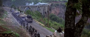 Movie still from “Force 10 from Navarone” (1978), directed by Guy Hamilton – A group of soldiers are walking across a bridge; Extreme Wide shot, High angle