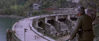 Movie still from “Force 10 from Navarone” (1978), directed by Guy Hamilton – A view of a dam from a bridge; Extreme Wide shot, High angle