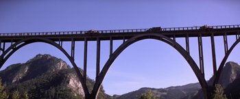 Movie still from “Force 10 from Navarone” (1978), directed by Guy Hamilton – A truck driving over a bridge over a river; Extreme Wide shot, Low angle