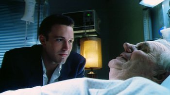 Movie still from “Forces of Nature” (1999), directed by Bronwen Hughes – A man in a suit looking at a person in a hospital bed; Close Up shot, Low angle