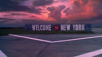Movie still from “Forces of Nature” (1999), directed by Bronwen Hughes – A sign that reads " welcome to new york " on the side of the road; Extreme Wide shot, Low angle