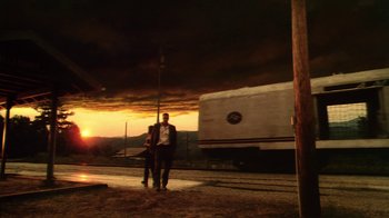 Movie still from “Forces of Nature” (1999), directed by Bronwen Hughes – A man standing next to another man on a train platform; Extreme Wide shot, Low angle