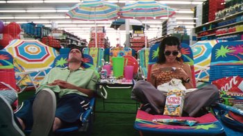 Movie still from “Forces of Nature” (1999), directed by Bronwen Hughes – A man and a woman sitting on lawn chairs under an umbrella; Wide shot, High angle