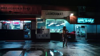 Movie still from “Forces of Nature” (1999), directed by Bronwen Hughes – A man standing in front of an ice cream shop at night; Extreme Wide shot, Low angle
