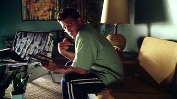 Movie still from “Forces of Nature” (1999), directed by Bronwen Hughes – A man sitting on the ground holding a remote control; Medium shot, Low angle