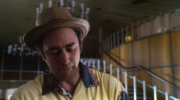 Movie still from “Forces of Nature” (1999), directed by Bronwen Hughes – A man wearing a straw hat standing in front of a staircase; Close Up shot, Low angle