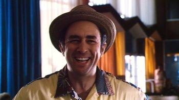 Movie still from “Forces of Nature” (1999), directed by Bronwen Hughes – A man wearing a straw hat smiling for the camera; Close Up shot, Low angle