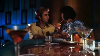 Movie still from “Forces of Nature” (1999), directed by Bronwen Hughes – A man and a woman sitting at a table with drinks; Medium shot, High angle