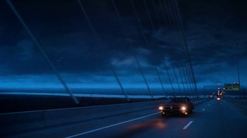 Movie still from “Forces of Nature” (1999), directed by Bronwen Hughes – A car driving on a highway under a cloudy sky at night; Extreme Wide shot, Low angle
