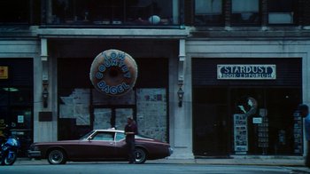 Movie still from “Forces of Nature” (1999), directed by Bronwen Hughes – A man standing in front of a doughnut shop; Extreme Wide shot, High angle