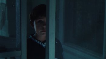 Movie still from “Forces of Nature” (1999), directed by Bronwen Hughes – A young boy looking out of a window at night; Close Up shot, Low angle