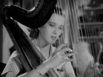 Movie still from “Four Daughters” (1938), directed by Michael Curtiz – A woman is playing a harp in a black and white photo; Close Up shot, Low angle