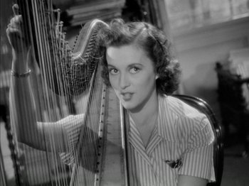 Movie still from “Four Daughters” (1938), directed by Michael Curtiz – A woman holding a harp in a room; Close Up shot, High angle