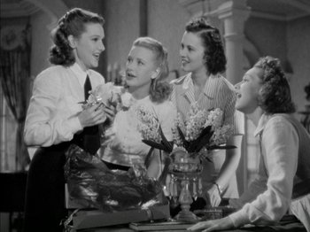 Movie still from “Four Daughters” (1938), directed by Michael Curtiz – A group of young women standing around a table; Medium shot, Low angle