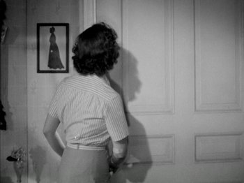 Movie still from “Four Daughters” (1938), directed by Michael Curtiz – A black and white photo of a woman standing in front of a door; Medium shot, Over the shoulder angle