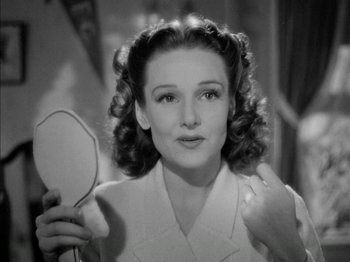 Movie still from “Four Daughters” (1938), directed by Michael Curtiz – A black and white photo of a woman holding a hand mirror; Close Up shot, Low angle