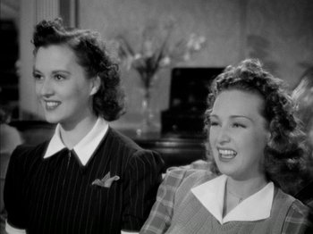 Movie still from “Four Daughters” (1938), directed by Michael Curtiz – Two young women smiling for the camera in a black and white photo; Medium shot, High angle