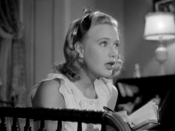 Movie still from “Four Daughters” (1938), directed by Michael Curtiz – A young girl sitting at a table reading a book; Close Up shot, High angle