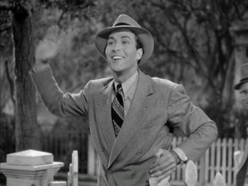 Movie still from “Four Daughters” (1938), directed by Michael Curtiz – A man in a suit and hat throwing a frisbee; Medium shot, Low angle