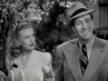 Movie still from “Four Daughters” (1938), directed by Michael Curtiz – A man and a woman standing next to each other in front of a tree; Close Up shot, Low angle