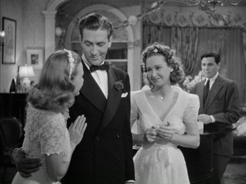 Movie still from “Four Daughters” (1938), directed by Michael Curtiz – A man and a woman standing next to each other in front of another woman; Medium shot, Over the shoulder angle