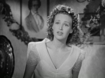 Movie still from “Four Daughters” (1938), directed by Michael Curtiz – A black and white photo of a woman with curly hair; Close Up shot, Over the shoulder angle