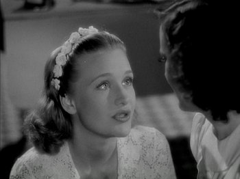 Movie still from “Four Daughters” (1938), directed by Michael Curtiz – A woman with a flower in her hair talking to another woman; Close Up shot, Over the shoulder angle