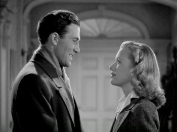 Movie still from “Four Daughters” (1938), directed by Michael Curtiz – A man and a woman standing next to each other in front of a building; Medium shot, Low angle