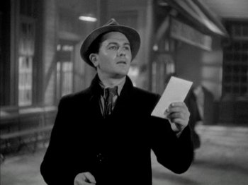 Movie still from “Four Daughters” (1938), directed by Michael Curtiz – A black and white photo of a man holding a piece of paper; Medium shot, Low angle