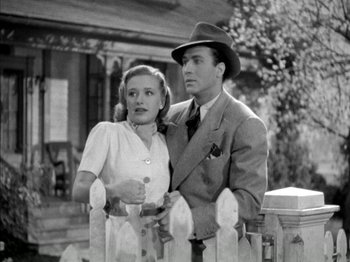 Movie still from “Four Daughters” (1938), directed by Michael Curtiz – A man and a woman standing next to each other in front of a picket fence; Medium shot, Low angle
