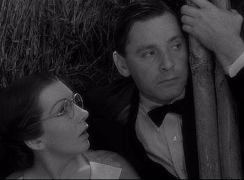Movie still from “Four Frightened People” (1934), directed by Cecil B. DeMille – A man and a woman sitting next to each other in front of a tree; Close Up shot, Low angle
