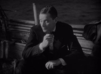 Movie still from “Four Frightened People” (1934), directed by Cecil B. DeMille – A black and white photo of a man sitting on a bench; Close Up shot, High angle